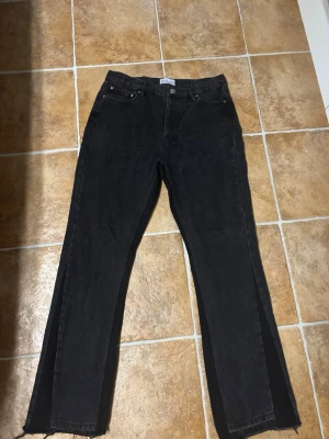 Bvaldi Svarta Flared Jeans Chrome Hearts buttons - W30 L32. Säljer ett par svarta jeans med rak passform och råa, fransiga benslut. Jeansen har klassisk femficksdesign och knappgylf. Materialet är denim i bomull och färgen är tvättad svart för en cool, avslappnad look.