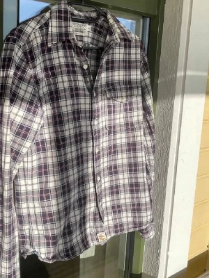 Ralph lauren skjorta - Snygg rutig skjorta i svart, vit och lila med klassisk krage och bröstficka. Skjortan är långärmad och har knappar framtill. Perfekt för en avslappnad och trendig look.