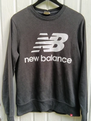 sweatshirt från New Balance - svart sweatshirt från New Balance med stort vitt logotryck på bröstet. Klassisk rund halsringning och ribbade muddar vid ärmslut och nederkant. Perfekt för en avslappnad och sportig stil. 