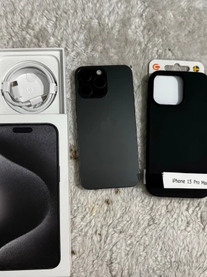 iPhone 15 Pro Max svart 256 Gb batteri 100% med nya tillbehör  - Säljer en iPhone 15 Pro Max i snygg svart färg. Telefonen har en stilren design med mattsvart baksida i glas och ram i metall. Tre stora kameror på baksidan och medföljande laddkabel och svart skal. Perfekt för dig som vill ha det senaste från Apple.