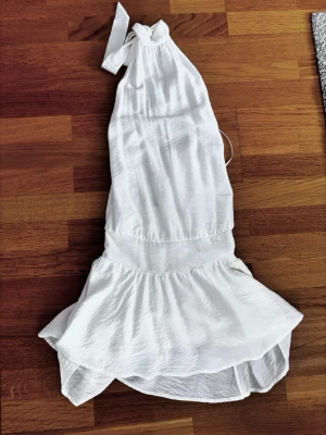 Vit halterneckklänning med volang - Jättesöt vit halterneck klänning, öppen rygg! Helt ny med prislappen kvar. Storlek M. Nypris 29.99€ (331,42 kr)