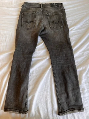 Grå raka jeans från Replay - Säljer ett par grå jeans från Replay med raka ben och klassisk femficksmodell. Jeansen har snygga slitningar och kontrastsömmar på bakfickorna. Tillverkade i mjukt denimtyg som ger en avslappnad look. Pris går att diskutera 