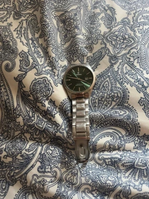 Festina classic klocka - Stilren klocka med grön urtavla och datumvisning. Armbandet är i silverfärgad metall och har en klassisk länkdesign. Perfekt accessoar för dig som gillar en tidlös look.