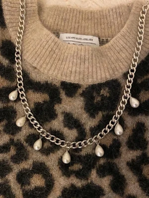 Silverfärgat halsband med droppformade pärlor - Snyggt halsband i silverfärgad metall med kedja och sju droppformade vita pärlor som hänger längs hela halsbandet. Perfekt accessoar för att lyfta din outfit med en trendig och elegant touch.