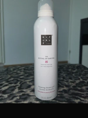 Rituals The Ritual of Sakura duschgel - Foaming shower gel från Rituals, The Ritual of Sakura. Vit flaska med svart och rosa text, innehåller rismjölk och körsbärsblom. Perfekt för dig som vill ha en lyxig och väldoftande duschupplevelse.