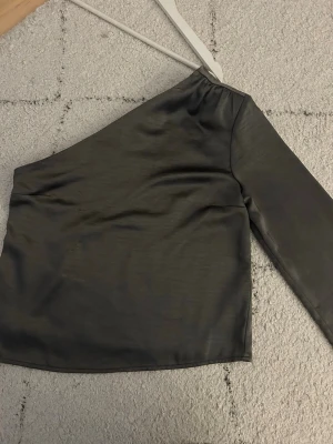 Oneshouldertopp - Silvrig/grå enarmad topp ifrån Gina tricot