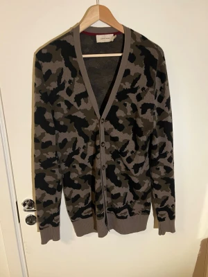 Ull kofta camo - Säljer en stickad kofta i Ull och bomull från Moods Of Norway. Den är i mycket bra skick utan någon defekt. Storlek Small. Den är i en schysst camouflage mönster.