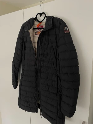Svart dunjacka från Parajumper - Säljer en svart långärmad dunjacka från Parajumpers med quiltad design och dragkedja framtill. Jackan har en klassisk look med logotyp på ärmen och ljus insida. Perfekt för kyliga dagar och enkel att matcha med olika outfits 💕som man ser på en bild finns de två små hål på den, men det är något som inte syns när man har på sig den och ifall man kan sy så går det säkert att fixa! ✨💕