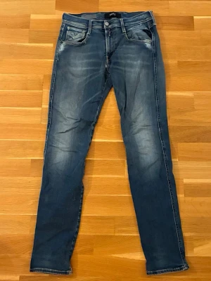 Blå slim fit jeans med slitningar - Säljer ett par blå slim fit jeans med snygga slitningar och tvättade detaljer. Modellen är hyper flex. Jeansen har fem fickor, smal passform och klassisk knappgylf. Jag har sytt ihop de vid skrevet men det ser bra ut så inget man tänker på. Perfekta för en avslappnad och trendig look. Storlek W30 L32 anbass