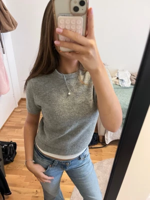 Grå kortärmad t-shirt från Zara - Mysig grå t-shirt från Zara i mjukt material. T-shirten har korta ärmar, rund halsringning och ribbade kanter. Perfekt till jeans eller kjol för en enkel och clean look.😊🪩⭐️