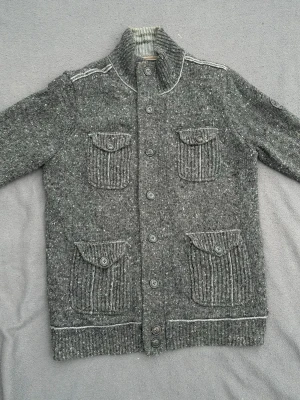 Unik fodrad cardigan - Sjukt snygg vintage cardigan med fyra fickor. Riktigt cleant stickat som ger ett schysst mönster. Fint skick, minimalt hål i höger armhåla, se bild 4. Storlek XL, sitter som L/XL. Rekommenderad längd är 187+ skulle jag säga.