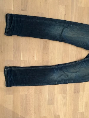 Mörkblå jeans från Replay - Snygga mörkblå jeans från Replay med klassisk femficksdesign och diskreta slitningar. Jeansen har smal passform och är tillverkade i denim med lätt stretch för extra komfort. Perfekta för en trendig och avslappnad look. Modell Rocco