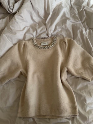 Beige stickad tröja från NEO NOIR 🤎 - Superfin beige stickad tröja från NEO NOIR med dekorativa pärlor/stenar runt halsen. Stilren och elegant modell som passar både till vardag och finare tillfällen.  Nypris 800 📏 Storlek: 34 ✨ Fint skick 🤎 Beige 💎 Fina detaljer vid halsringningen  Skriv gärna vid intresse! 💌