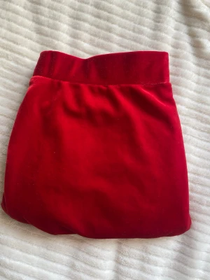 Röd sammetskjol från Ellos - Snygg röd sammetskjol från Ellos med bred resår i midjan. Kjolen har en mjuk och glansig yta som ger en lyxig känsla och passar perfekt till olika outfits. Enkel och stilren design som är lätt att matcha.
