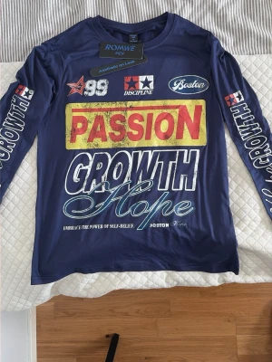 Blå långärmad t-shirt med tryck - Säljer en blå långärmad t-shirt från ROMWE med stora tryck fram och bak. Framsidan har text som 'PASSION', 'GROWTH' och 'Hope' i olika färger och stilar, samt flera grafiska detaljer. Baksidan har stort '99' och stjärna. Materialet är mjukt och stretchigt