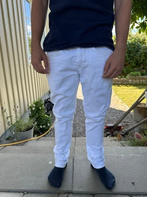 Vita slim fit jeans från Dondup - Säljer ett par vita slim fit jeans från Dondup. Jeansen har klassisk femficksmodell, knappgylf och är tillverkade i ett mjukt bomullstyg med lite stretch. Snygg passform som sitter tajt längs benen och passar perfekt till en trendig streetwear-look.