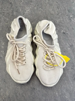 Beige chunky sneakers med mesh - Säljer ett par beige sneakers med unik chunky sula och mesh-ovandel. Skorna har snörning och stickad strumpliknande kant för skön passform. Snygg futuristisk design som sticker ut och passar perfekt till streetwear.