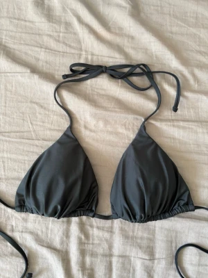 Svart bikinitopp - Stilren svart trekantsbikini med knyt i nacken och ryggen. Klassisk modell som passar perfekt till stranden eller poolen. Tillverkad i mjukt syntetmaterial som torkar snabbt och sitter bekvämt.