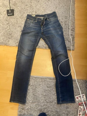 Mörkblå raka faded jeans från Levi's - Snygga mörkblå jeans från Levi's med raka ben och klassisk femficksmodell. Jeansen har subtila slitningar och kontrastsömmar samt en brun patch bak i midjan. Tillverkade i slitstark denim som ger en tidlös look.