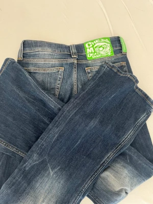 Blå jeans från cheapmonday - Snygga blå jeans med slitningar och en cool grön patch med tryck baktill i midjan. Klassisk femficksmodell med dragkedja och knapp. Jeansen har en smal passform och är tillverkade i denim med lätt stretch.