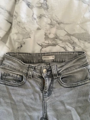 Ljusgrå lågmidjade jeans - Ljusgrå lågmidjade jeans från perfekt jeans/Gina Tricot, dom har slitningar där nere eftersom att jag sprättade upp dom så dom skulle bli längre men det går ju att sy upp igen 💞 skriv för mer bilder eller prisförslag 
