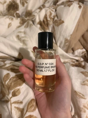 E.D.P. N°024 parfym 50 ml - Säljer en stilren parfymflaska på 50 ml från The Perfume Brand. Flaskan är cylindrisk i genomskinligt glas med svart plastlock och innehåller en ljusgul vätska. Enkel och modern design som passar perfekt i väskan. Det luktar baccarat rouge.