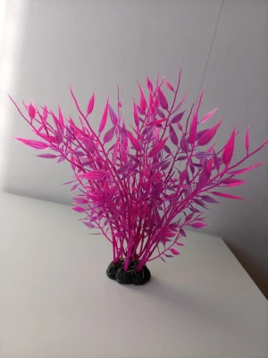 Plastväxt till akvarium, neonrosa - Säljer en dekorativ plastväxt i neonrosa färg med smala blad och svart fot. Perfekt som dekoration i akvarium eller terrarium. Växten är gjord av plast och har en naturtrogen form som ger färg till ditt vattenlandskap.