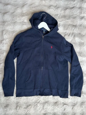 Ralph Lauren zip hoodie - Mörblå zip hoodie från Ralph Lauren. Köpt på kidsbrandstore för ca 1200. Storlek XL (kids) men skulle säga att den passar en vanlig S. Skriv vid frågor!