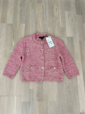 Rosa melerad kofta med guldknappar - Trendig rosa och melerad kofta med raka ärmar och dekorativa guldknappar framtill. Perfekt för dig som vill ha en mysig men ändå stylish look. Verkligen så söt och elegant!!