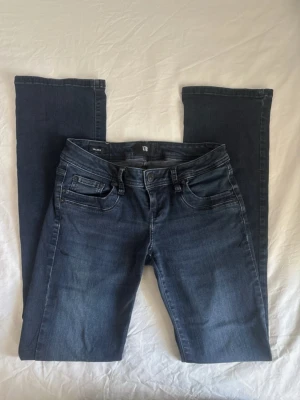 Mörkblå raka jeans - Säljer ett par mörkblå jeans med rak passform och klassisk femficksdesign. Jeansen har subtila slitningar och kontrastsömmar för en snygg look. Perfekta till en avslappnad stil och passar till det mesta i garderoben.