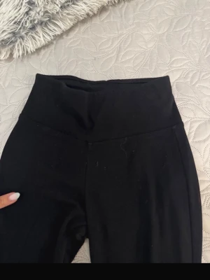 Svarta leggings från Gina Tricot - Ett par svarta leggings från Gina Tricot med hög midja och stretchigt material. Perfekta för en avslappnad look eller till träning. Klassisk design utan synliga detaljer eller fickor.