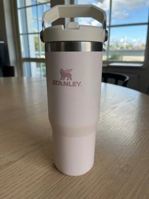 Ljus rosa termosmugg från Stanley - Snygg ljus rosa termosmugg från Stanley med praktiskt handtag och rostfri kant upptill. Muggen har en stilren design och är tillverkad i rostfritt stål med matt finish. Perfekt för att hålla drycken varm eller kall under dagen.