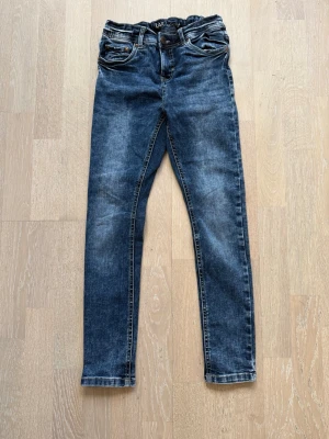 Mörkblå slim fit jeans - Snygga mörkblå slim fit jeans med klassisk femficksdesign och normal midja. Jeansen har lätt slitna detaljer och smal passform hela vägen ner. Perfekta för en trendig och avslappnad look.