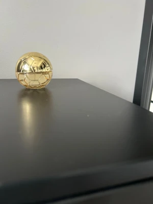 Guldfärgad parfymflaska i bollform - Unik parfymflaska i form av en fotboll, helt i blank guldfärg. Flaskan har en rund och kompakt design som verkligen sticker ut på hyllan. Perfekt för dig som gillar sportiga och coola detaljer i badrummet.