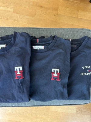 3 st Mörkblå T-shirt Tommy Hilfiger samtliga i storlek 164 - Säljer 3  mörkblå T-shirt från Tommy Hilfiger. 2 med  klassisk TH-logga broderad i vitt och rött på bröstet. En med med större tryck. 