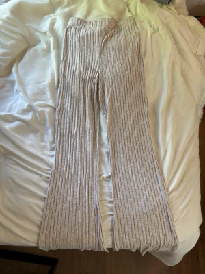 Beige ribbade mjukisbyxor med utsvängda ben - Supersköna beige mjukisbyxor med ribbad struktur och utsvängda ben. Byxorna har resår i midjan och är gjorda i ett mjukt, stretchigt material som känns riktigt bekvämt. Perfekta för chill dagar hemma eller när du vill ha en avslappnad look. Storlek 34/36 men är väldigt stretchiga. 