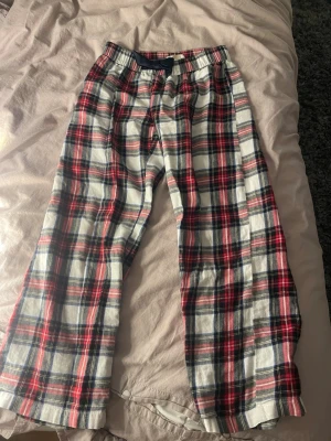 Rutiga pyjamasbyxor i bomull - Mysiga pyjamasbyxor med rött, vitt och blått rutmönster. Byxorna har resår i midjan och raka ben, perfekta att sova i eller bara chilla. Tillverkade i mjuk bomull som känns skön mot huden.