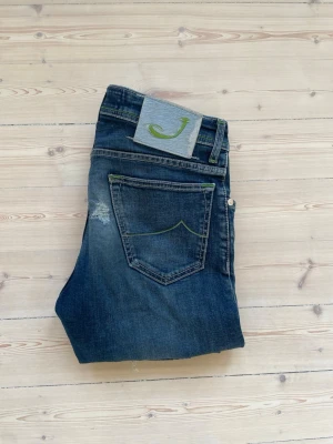 Jacob Cohën Jeans - Säljer nu dessa mörkblåa Jacob Cohën jeans i modellen 688. Jeansen är i storlek 29 och är i ett så använt skick. Jeansen har 2 tydliga hål vid de bakre fickorna (se sista bild). Det går säkert att laga, fläcke vid de bakre fickorna går bort med en tvätt (kan tvättas på begäran) därav priset på jeansen. 