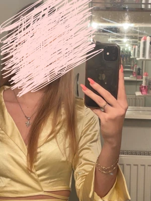 Ljusgul omlottopp med krage - Trendig ljusgul omlottopp med krage och långa ärmar. Toppen har croppad passform och knytband i midjan för en snygg siluett. Materialet är glansigt och känns mjukt mot huden. Perfekt för dig som vill sticka ut med en unik topp.