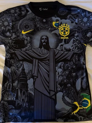 Svart Brasil Neymar fotbollströja - Unik svart Brasilien fotbollströja från Nike med Neymar 10 på ryggen. Tröjan har ett detaljerat grafiskt tryck med Kristusstatyn, gula detaljer och Brasil-logga på bröstet. storlek s passar på m