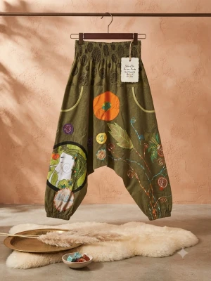 Gröna boho-byxor med färgglada mönster - Unika gröna byxor med lös passform och resår i midjan. Dekorerade med färgglada broderier, applikationer och tryck i orange, gult, blått och grönt. Byxorna har stora fickor och bohemisk känsla med konstnärliga detaljer och elastiska benslut. Perfekta för dig som gillar statement-plagg.
