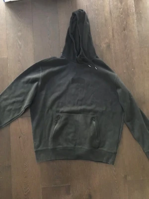 Svart hoodie från Hollister - Snygg svart hoodie från Hollister med broderad logga på bröstet. Hoodien har dragkedjeförsedda fickor framtill och en klassisk huva med dragsko. Tillverkad i mjukt material som passar perfekt för en avslappnad stil.