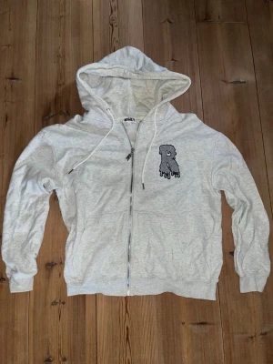 Ljusgrå zip hoodie från RISKY - Ljusgrå hoodie med dragkedja och huva från RISKY limited edition. På bröstet finns ett tryck av en droppande bokstav. Hoodien har dragsko i huvan och ribbade muddar vid ärmar och nederkant. Perfekt för en avslappnad och cool stilren outfit. Hoodien är aldrig använd då den inte var min stil och den säljs även inte heller längre!   Nypris:850kr  Mitt pris:710kr