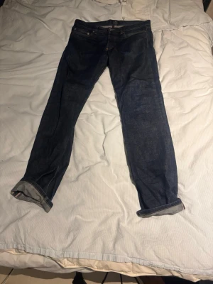 Mörkblå jeans från A.P.C. New Standard - Säljer ett par klassiska mörkblå jeans från A.P.C. modellen New Standard. Raka ben, fem fickor och uppvikta benslut för en clean look. Tillverkade i rå denim som formar sig efter kroppen. Perfekta för dig som gillar minimalistisk och tidlös stil.