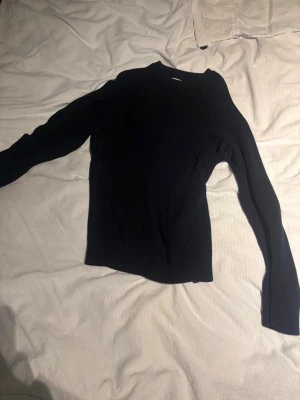 Mörkblå stickad tröja från NN07 - Snygg mörkblå stickad tröja från NN07 med rund hals och ribbad struktur. Perfekt till höst och vinter för en clean och stilren look. Tröjan har långa ärmar och är gjord i ett mjukt material som känns skönt mot huden.