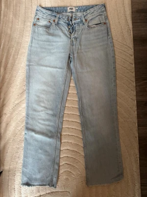 Ljusblå raka jeans - Säljer ett par ljusblå jeans med rak passform och klassisk femficksdesign. Jeansen har normal midja och stängs med dragkedja och knapp. Perfekta för en avslappnad och trendig look.