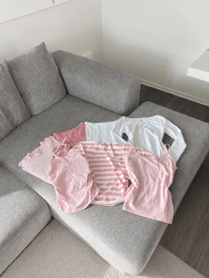 klädpakey rosa - 7 toppar💗 - Säljer ett paket med 7 toppar i olika nyanser av rosa och vitt. En av t-shirtsen har rosa och vita ränder, resten är enfärgade. Alla har korta ärmar och är i mjuk bomull, perfekta för en avslappnad stil.