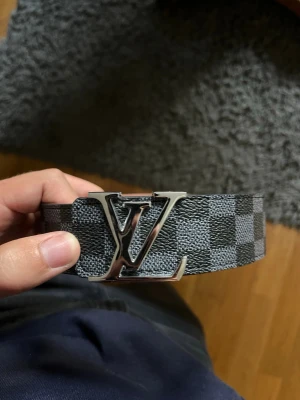 Svart Lyxbälte LV - Snyggt Lyxbälte. Svart med rutor. Ett snyggt silvrigt LV märke på. 110cm passar till många outfits. Ger en lyxig look. Knappt använt! 