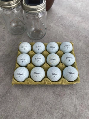 12 vita Titleist golfbollar Pro V1 - Säljer ett set med 12 vita golfbollar från Titleist, modell Pro V1. Perfekta för dig som vill ha kvalitetsbollar till golfbanan. Skicket på bollarna varierar men alla är fullt spelbara. Obs! Inte exakt de bollar som syns på bild. 
