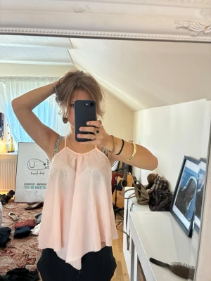 Ljusrosa flowy linnetopp - Säljer en ljusrosa, flowy linnetopp med tunna axelband och lös passform. Toppen har en luftig och somrig känsla, perfekt för varma dagar. Materialet känns lätt och svalt mot huden.